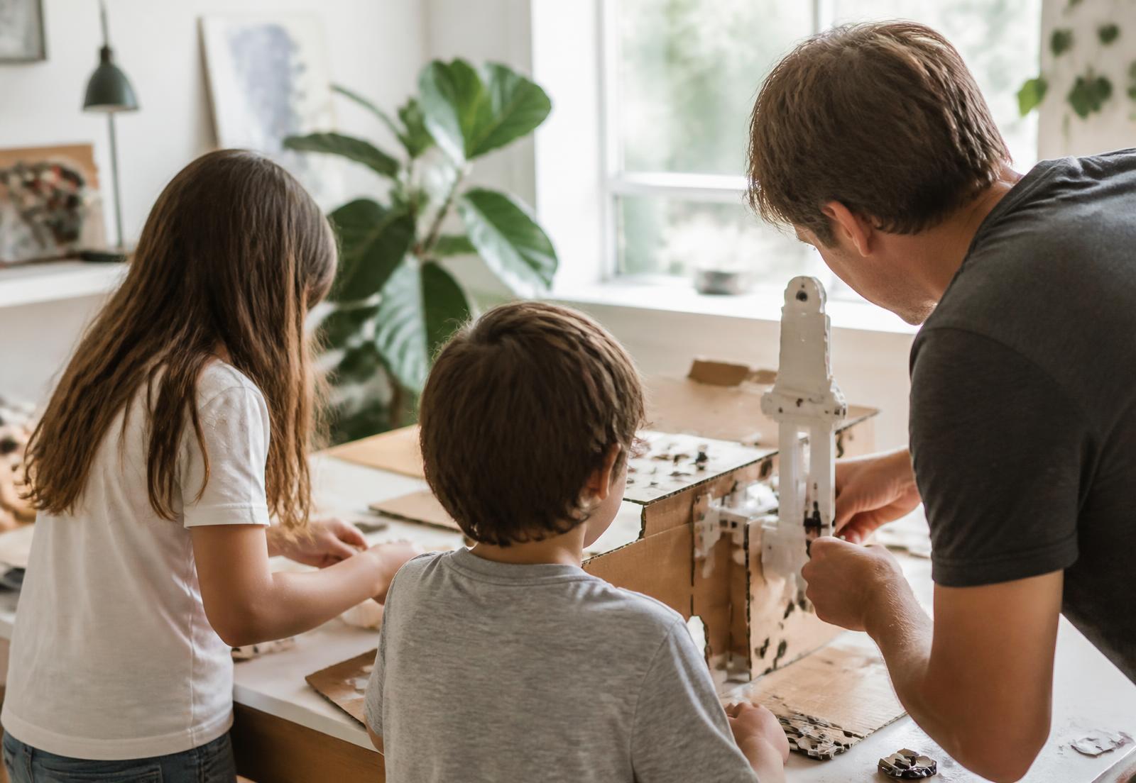 Família montando um projeto de papelão sobre a mesa